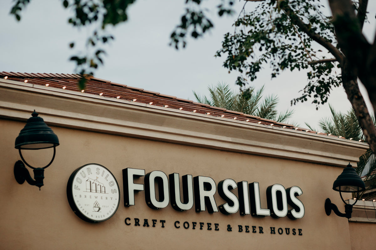 Four Silos Craft Coffee & Beer House sign on a building exterior with palm trees in the background.